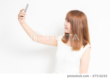 A woman wearing a dress taking a selfie with a smartphone A woman wearing a dress taking a selfie with a smartphone 67518283