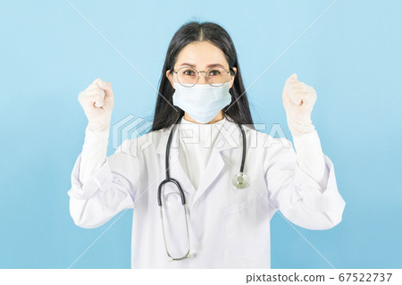 Smart young asian woman doctor in lab coat with Medical face mask,white latex medical gloves and stethoscope against blue background,health care concept 67522737
