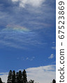 A landscape with rainbow clouds reflected in the blue sky 67523869