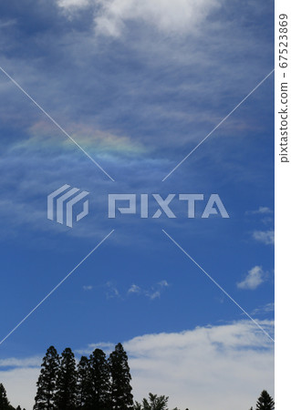 A landscape with rainbow clouds reflected in the blue sky 67523869