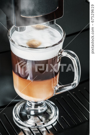 cup with hot cappuccino with foam prepared in the coffee machine 67529619