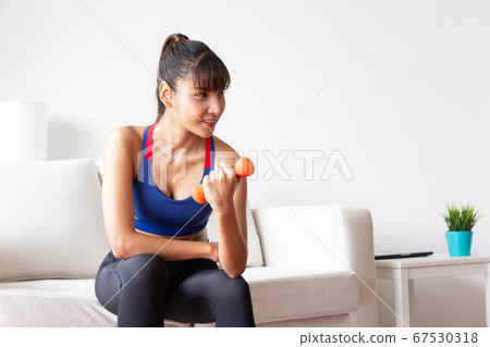 Sporty girl having weight exercise at home 67530318