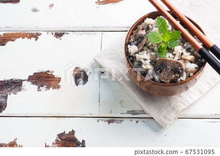 Risotto with mushrooms on a wooden plate and chopsticks. Boiled white rice with champignons in cream sauce. Light wooden background. Copy space Risotto with mushrooms on a wooden plate and chopsticks. Boiled white rice with champignons in cream sauce. Light wooden background. Copy space 67531095