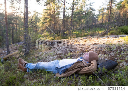 Man lies on the grass, resting in the middle of the forest relaxing Man lies on the grass, resting in the middle of the forest relaxing 67531314
