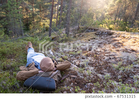 Man lies on the grass, resting in the middle of the forest relaxing Man lies on the grass, resting in the middle of the forest relaxing 67531315