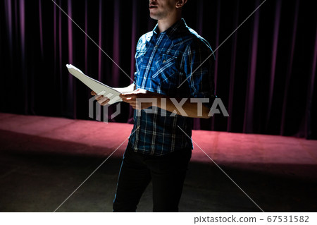 Stand up comedian on stage. Young man talks joke into microphone or sings songs. Stand up comedian on stage. Young man talks joke into microphone or sings songs. 67531582