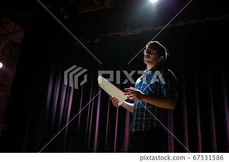 Stand up comedian on stage. Young man talks joke into microphone or sings songs. Stand up comedian on stage. Young man talks joke into microphone or sings songs. 67531586