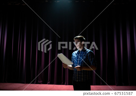 Stand up comedian on stage. Young man talks joke into microphone or sings songs. Stand up comedian on stage. Young man talks joke into microphone or sings songs. 67531587