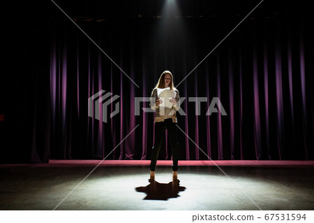 Low angle view of a young woman reading script on stage 67531594
