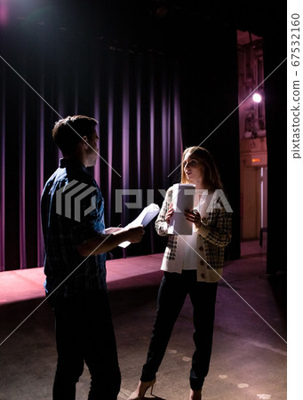 Two young actors rehearsing a scene on stage, dark lighting 67532160