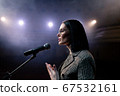 Portrait of women speaking through a microphone in dark conference hall. woman talks into microphones at press conference. Profile of mature female politician speaking passionately from tribune 67532161