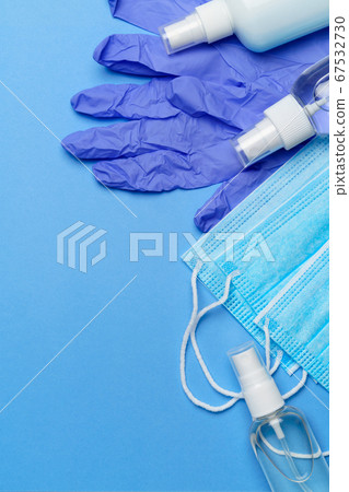 bottle of lotion, sanitizer or liquid soap, latex rubber gloves, hat and protective mask over blue background - flat layout bottle of lotion, sanitizer or liquid soap, latex rubber gloves, hat and protective mask over blue background - flat layout 67532730