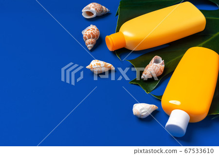 Bright yellow bottles of sunscreen product on dark blue paper background 67533610