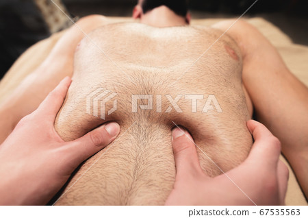 Close-up professional massage of the diaphragm to a man in a professional massage room. The concept of internal organs and abdominal cavity 67535563