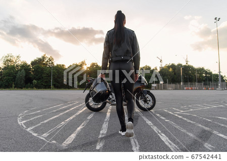 girl with long hair in a leather jacket in an underground parking lot on a motorcycle 67542441