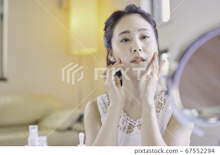 一名年輕女子在客廳裡照顧她的皮膚[擔心] 67552294