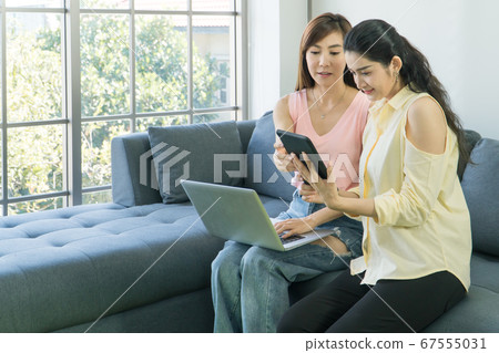 Adult Asian women are using technology together. 67555031