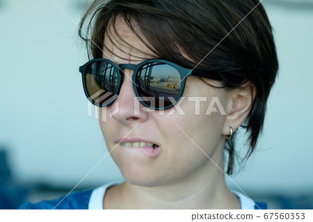 A woman is afraid to fly. She looks at the plane A woman is afraid to fly. She looks at the plane 67560353