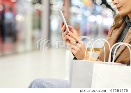 Hands of young elegant female shopper looking through adverts in the phone 67561476
