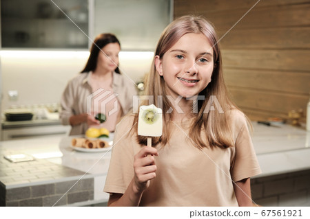 Pretty blond teenage girl showing you homemade eskimo icecream with kiwi 67561921