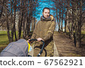 beautiful and young woman mother and baby in a stroller walking in the park 67562921