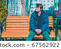 Middle-aged man resting in a garden on a wooden bench enjoying life and weather. 67562922