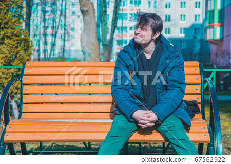 Middle-aged man resting in a garden on a wooden bench enjoying life and weather. Middle-aged man resting in a garden on a wooden bench enjoying life and weather. 67562922