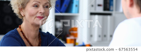 Happy elderly woman measures pressure at doctor 67563554