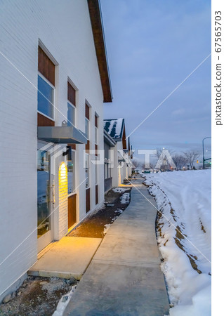 Pathway along homes and snowy ground in winter 67565703