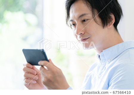 A man watching video distribution on a smartphone 67566410
