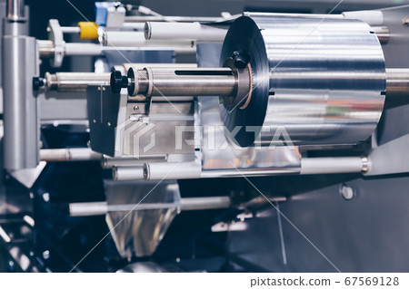 roll of aluminum foil for food packaging on the automatic packing machine in food product factory. industrial and technology concept. 67569128