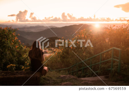 Blurred image , Lonely woman sitting and watching the sunset Blurred image , Lonely woman sitting and watching the sunset 67569559