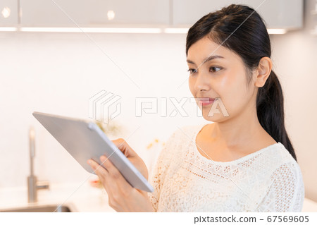 女人在廚房裡操作平板電腦 女人在廚房裡操作平板電腦 67569605
