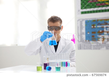 A male chemist holds test tube of glass in his hand overflows a liquid solution A male chemist holds test tube of glass in his hand overflows a liquid solution 67569874