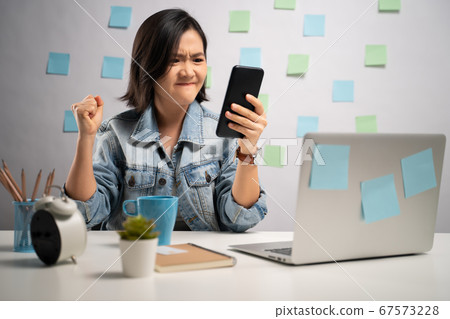 Asian woman angry looking at smart phone reading 67573228