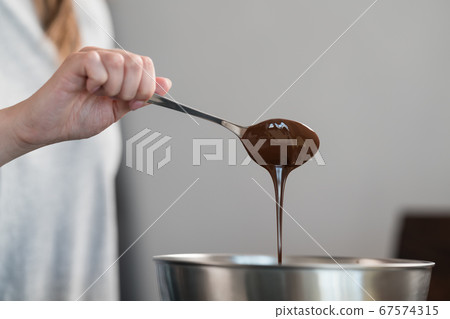 young woman mixing chocolate in steel bowl to make candys 67574315