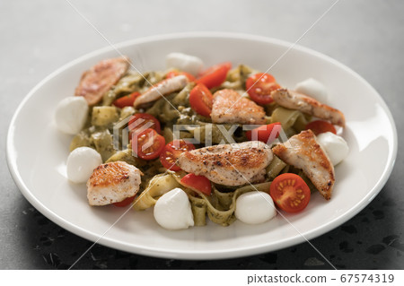 fettuccine with pesto, tomatoes , mozzarella and chicken on white plate 67574319