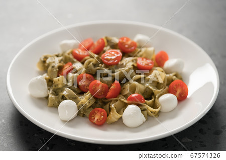 fettuccine with pesto, tomatoes and mozzarella on white plate 67574326
