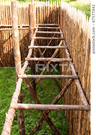 Traditional Slavic Russian Belarus rustic country round log house and a fence building process. A photo in summer sunny day with green grass warm weather 67577842