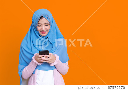 Smiling Asian muslim woman with using mobile or Smiling Asian muslim woman with using mobile or 67579270