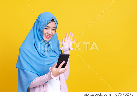 Smiling Asian muslim woman with using mobile or Smiling Asian muslim woman with using mobile or 67579273