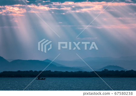 Cloudscape at sunset over lake Malawi with sun beams and fisherman Cloudscape at sunset over lake Malawi with sun beams and fisherman 67580238