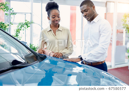 handsome afro man shows to wife a car he is liked handsome afro man shows to wife a car he is liked 67580377