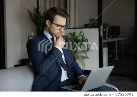 Serious Caucasian businessman look at laptop screen thinking 67580742
