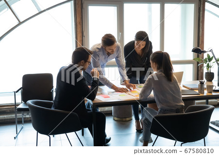 Diverse colleagues brainstorm discuss company paperwork at meeting Diverse colleagues brainstorm discuss company paperwork at meeting 67580810