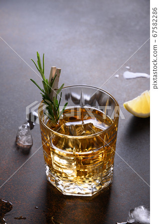One shot of whiskey with rosemary on dark. Vertical orientation. One shot of whiskey with rosemary on dark. Vertical orientation. 67582286