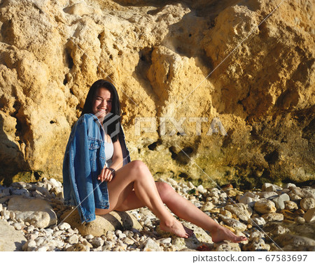 portrait of a woman in a denim jacket on a background of yellow rock 67583697