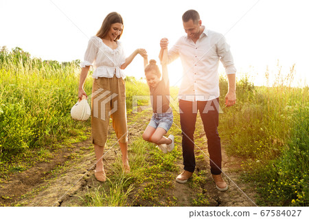 Happy parents and kid walking together in summer Happy parents and kid walking together in summer 67584027