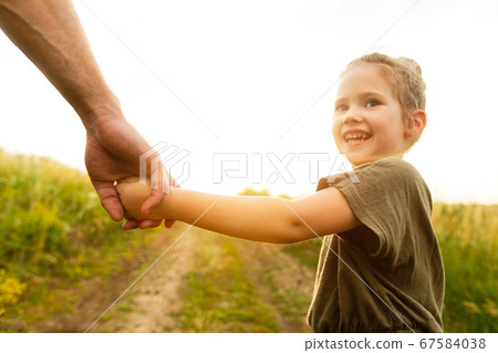 Little girl holding her dad's hand and looking back Little girl holding her dad's hand and looking back 67584038