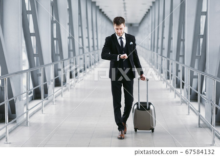 Adult business man standing in airport with suitcase 67584132